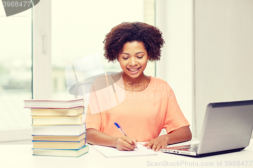 Image of happy african american woman with laptop at home