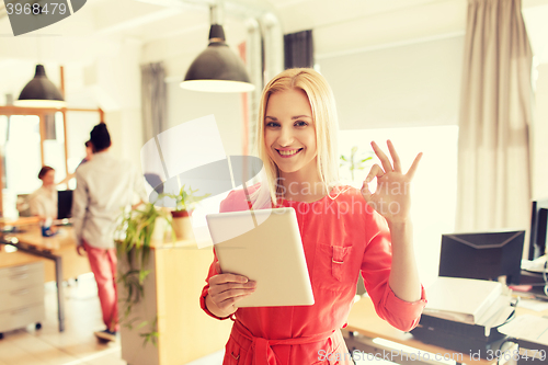 Image of woman with tablet pc showing ok sign at office
