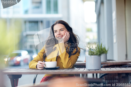 Image of happy woman drinking cocoa at city street cafe