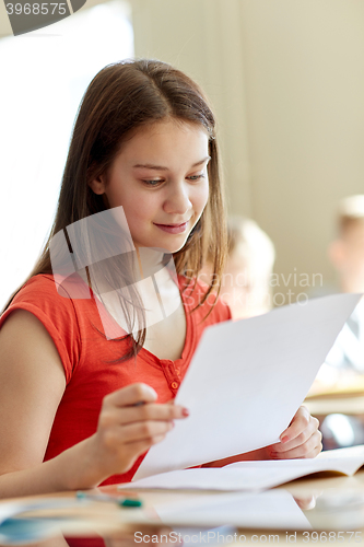 Image of happy student girl with test paper at school