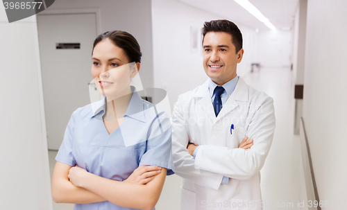 Image of smiling doctor in white coat and nurse at hospital