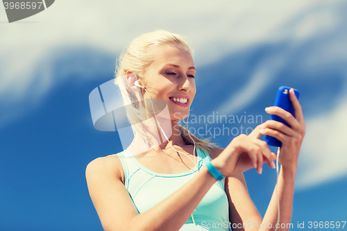 Image of happy woman with smartphone and earphones outdoors