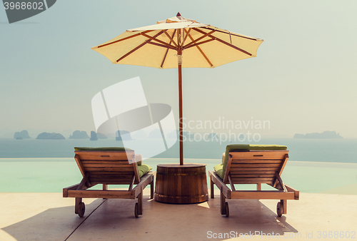 Image of infinity pool with parasol and sun beds at seaside