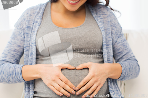 Image of close up of happy pregnant woman making heart