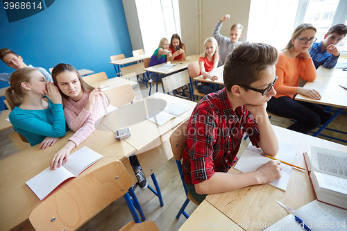 Image of students gossiping behind classmate back at school