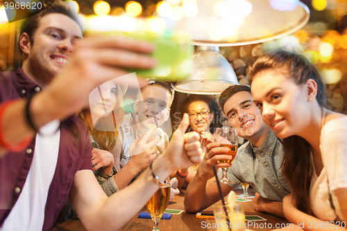 Image of happy friends with smartphone taking selfie at bar