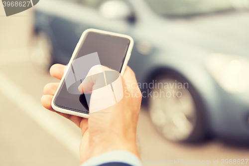 Image of close up of man hand with smartphone and car