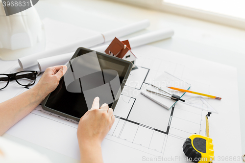 Image of close up of hand with blueprint and tablet pc