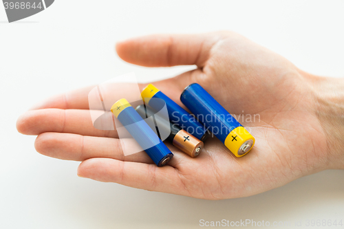 Image of close up of hands holding alkaline batteries heap