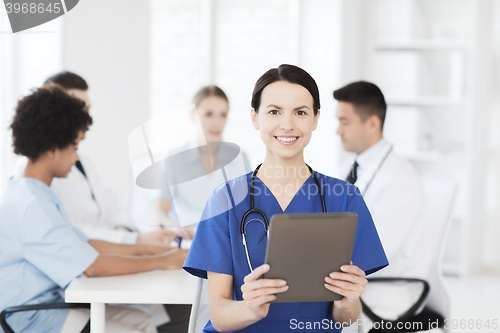 Image of happy doctor with tablet pc over team at clinic