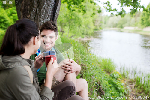 Image of happy couple with cups drinking in nature