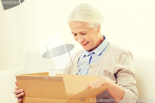 Image of happy senior woman with parcel box at home