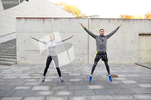 Image of happy man and woman jumping outdoors