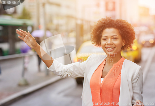 Image of happy african woman catching taxi