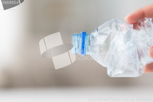 Image of close up of hand holding used plastic bottle