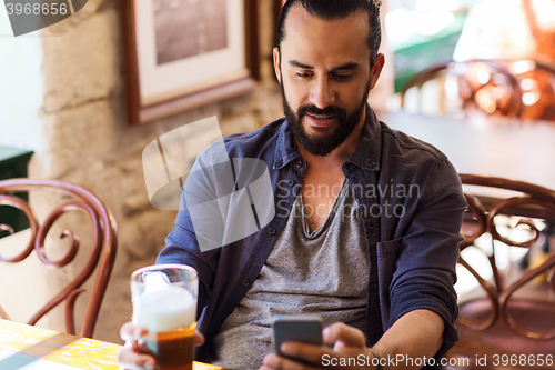 Image of man with smartphone drinking beer at bar or pub