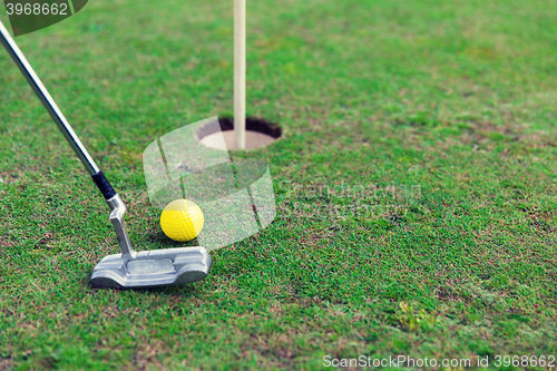 Image of close up of club and ball near hole on golf field