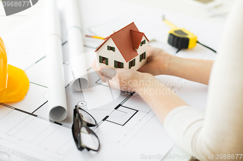 Image of close up of hands with house model above blueprint