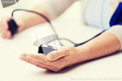 Image of old woman with tonometer checking blood pressure