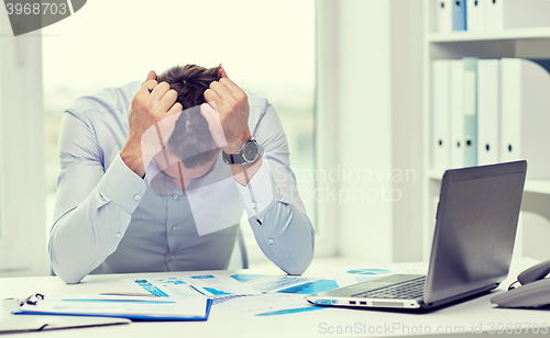 Image of stressed businessman with papers in office