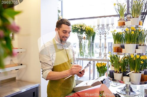 Image of florist man with clipboard at flower shop counter