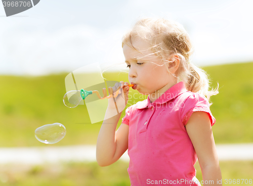 Image of little girl blowing soap bubbles outdoors