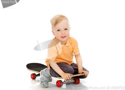 Image of happy little boy sitting on skateboard