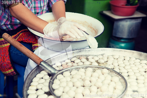 Image of close up of cook frying meatballs at street market