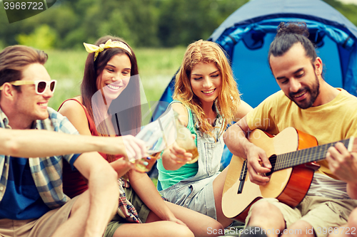 Image of happy friends with drinks and guitar at camping