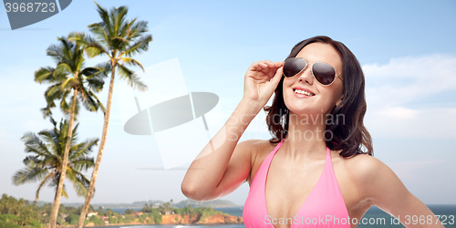 Image of happy woman in sunglasses and bikini on beach