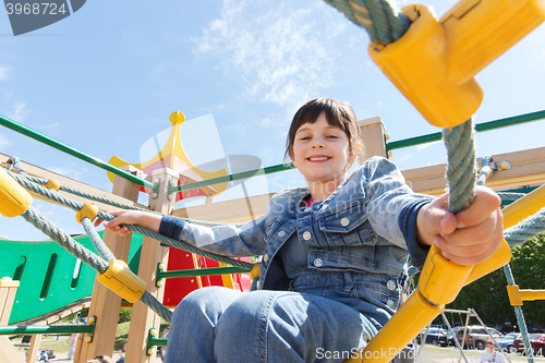 Image of happy little girl climbing on children playground