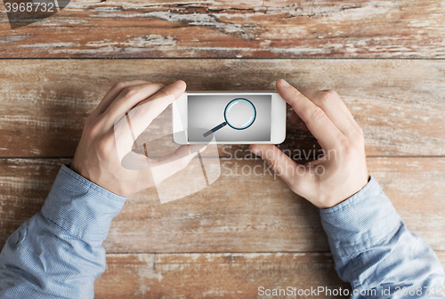 Image of close up of hands with magnifier on smartphone