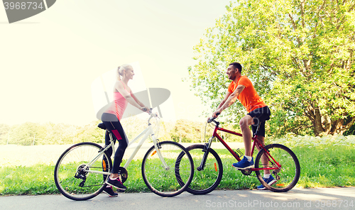 Image of happy couple riding bicycle outdoors