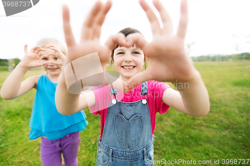 Image of happy kids showing heart shape sign outdoors