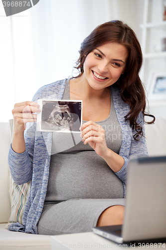 Image of happy pregnant woman with ultrasound image at home