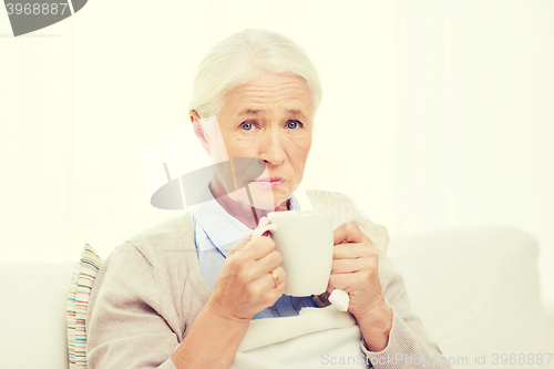 Image of sick senior woman drinking hot tea at home