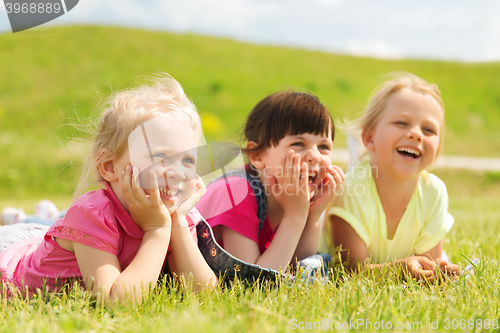 Image of group of kids lying on blanket or cover outdoors