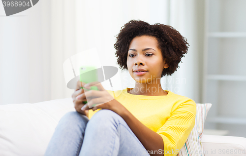 Image of happy african woman with smartphone at home