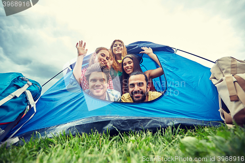 Image of happy friends with backpacks in tent at camping