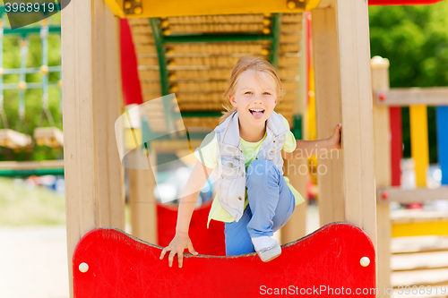 Image of happy little girl climbing on children playground