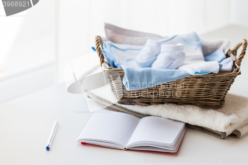 Image of close up of baby clothes for newborn and notebook