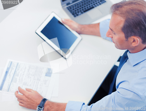 Image of businessman with tablet pc and papers in office