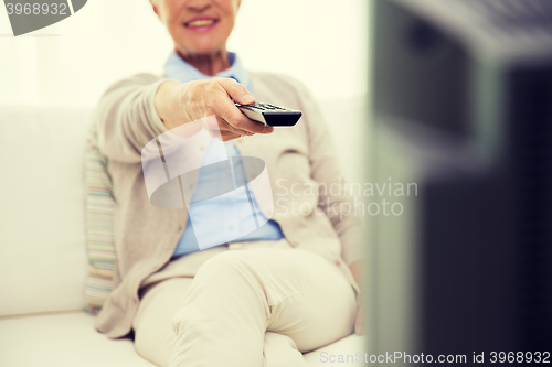 Image of close up of happy senior woman watching tv at home