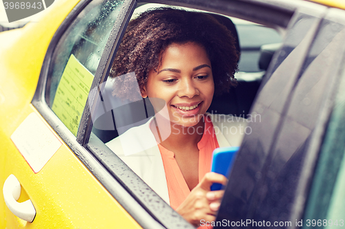 Image of happy african woman texing on smartphone in taxi