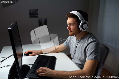 Image of man in headset playing computer video game at home