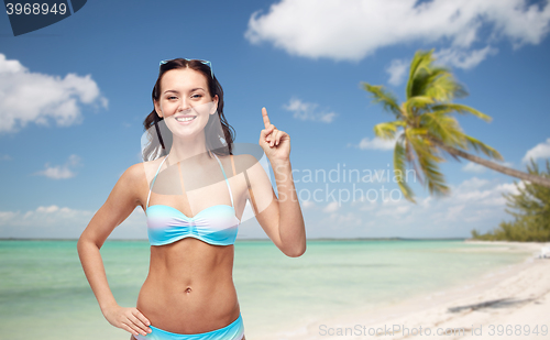 Image of happy woman in bikini swimsuit pointing finger up