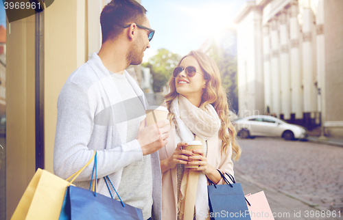 Image of happy couple with shopping bags and coffee in city