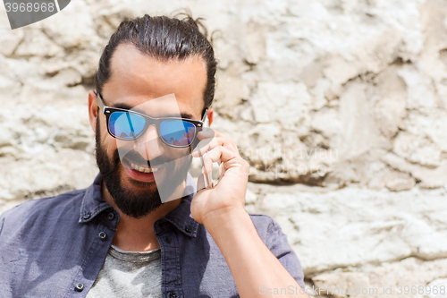 Image of smiling man with smartphone calling on city street