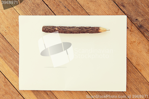 Image of white blank paper sheet with wooden pen on table 