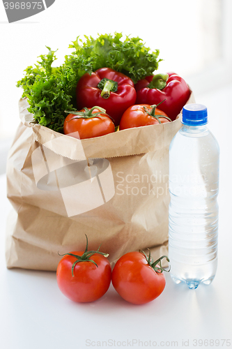 Image of close up of paper bag with vegetables and water